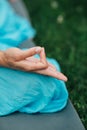 Woman meditating in lotus position closeup. Hands close-up mudra. Sitting on rug the lawn of green grass background Royalty Free Stock Photo