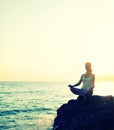 Woman meditating in lotus yoga on beach
