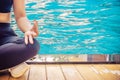 Woman meditating in a lotus yoga position at swimming pool