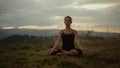 Woman meditating in mountains at sunset. Girl sitting in lotus pose on ground Royalty Free Stock Photo