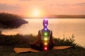 Woman meditating near river in twilight, back view. Scheme of seven chakras