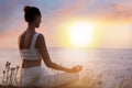 Woman meditating near sea at sunset. Practicing yoga Royalty Free Stock Photo