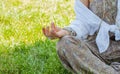 Woman is meditating sitting in Lotus pose on grass at the park. Boho style with accessories, rings and bracelets