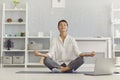 Woman meditating in the workplace sitting in front of a laptop practicing stress relief exercises. Royalty Free Stock Photo
