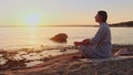 Woman meditating, zen yoga meditation practice breath exercise in nature. Yogi girl is sitting in sunset, healthy