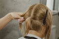 Woman with medium long blonde hair. With a short haircut at the hairdresser at the stylist using scissors. Care procedures. The Royalty Free Stock Photo