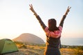 Woman meets the dawn in the mountains, rejoices in the sun. Panoramic view of the mountain and the sea from above. Camping, Royalty Free Stock Photo