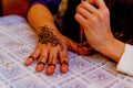 Woman mehendi artist painting henna on the hand.