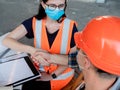 Builders in helmets, vests and medical masks shake hands after signing the contract for the construction of the building