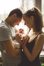 Woman and man holding on hands a newborn. On the background window. Mom, dad and baby. Portrait of young family. Happy family life Royalty Free Stock Photo