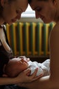 Woman and man holding on hands a newborn. Mom, dad and baby. Happy family life. Man was born. On the background window and heating Royalty Free Stock Photo