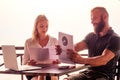 Woman and man in summer cafe by the sea working with laptop and charts schedule business partners abroad