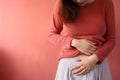 Woman with menstrual cramps clutching stomach in pain in fornt of studio background