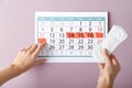 Woman with menstrual pad and calendar on color background