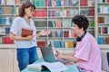 Woman mentor teaching male student in college library, exam preparation Royalty Free Stock Photo