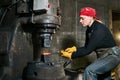 Woman metal artist processes a hot workpiece with a power hammer