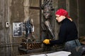 Woman metal artist at work in workshop using metalcut saw
