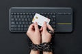 Woman with metal chain holding credit card over keyboard, online shopping addiction concept