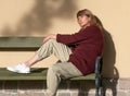 Woman, middle-aged, sad, pretty, blonde hair, with a pensive look, sits on a bench Royalty Free Stock Photo