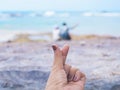 Woman mini hand heart shape over couple sitting on summer beach background