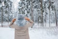 woman mittens dressed fashionable gray stands with her back makes heart gesture with her hands against background snowy