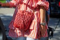 Woman with Miu Miu red leather bag, white and red striped shirt and Rolex Submariner watch