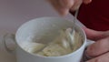 A woman mixes a cream cheese to lubricate the wafer cake layers.