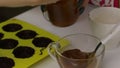 Woman mixes the filling for glazed sweets. Nearby is a silicone mold lubricated with liquid chocolate