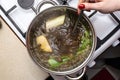 The woman mixes the mushroom soup with a metal spoon which is in a metal pot on the gas stove, top view. Royalty Free Stock Photo