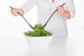 Woman mixing arugula salad in square bowl