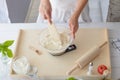 Woman mixing pizza dough with wooden spatula.