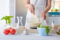 Woman mixing pizza dough with wooden spatula.