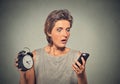 Woman with mobile phone and alarm clock stressed running late