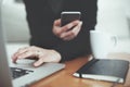 Woman with mobile phone and laptop. Manager researching project at office, a book and cup of coffee. Soft focus image