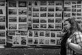 A woman on a mobile phone walks passed a collection of black and white images for sale on the streers of Galway, Ireland