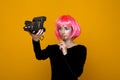 Woman model in the yellow studio with lollipop in a pink wig and bright clothes. Royalty Free Stock Photo