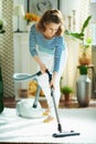 Woman at modern home in sunny day vacuuming white fluffy carpet