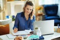 Woman in modern house in sunny day talking on phone and working Royalty Free Stock Photo