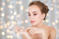 Woman with moisturizing cream on hand over lights Royalty Free Stock Photo