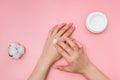 Woman moisturizing her hand with cosmetic cream with copy space on pink background in minimalism style. Royalty Free Stock Photo