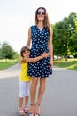 Woman mom walks with her daughter in summer in city park. Little girl 5-7 years old, hugs her mumu, happy smiles