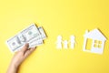 Woman with money and paper silhouettes of family and house on color background, top view.