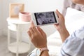 Woman monitoring modern cctv cameras on smartphone indoors