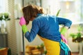 Woman with mop having back pain at home in sunny day