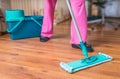 Woman is mopping wooden floor with mop