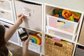 Woman mother applying paper sticker with name title on basket container clean out of childish toys