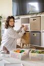 Woman mother applying paper sticker with name title on basket container clean out of childish toys