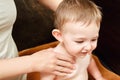 Woman mother giving massage to happy toddler baby sitting on brown Royalty Free Stock Photo