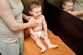 Woman mother giving massage to happy toddler baby sitting on brown Royalty Free Stock Photo