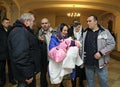 Woman mother holding baby on hands, father and relatives standing near. Ukrainian traditional ceremony christening for